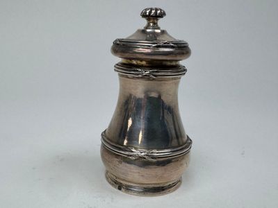 une petite poivrière en argent posée sur une surface blanche
