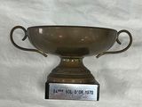 un trophée en bronze sur fond blanc, sur lequel est apposée une étiquette indiquant son prix