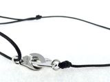 un gros plan sur un bracelet en cordon noir muni d'un fermoir en argent