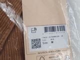 a label on a brown sweater that is on a plastic bag