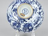 a blue and white bowl with a gold rim on a stand