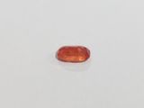 an orange sapphire stone on a white surface