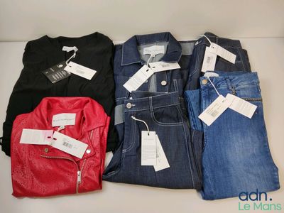 quatre paires de jeans pour homme posées sur une table, avec leurs étiquettes de prix