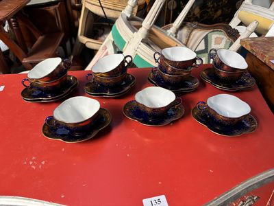 Plusieurs tasses et soucoupes sont posées sur une table rouge, accompagnées d'une étiquette de prix