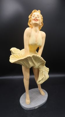 statue d'une femme en maillot de bain jaune posée sur un socle blanc