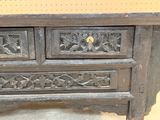 a wooden chest of drawers that has carvings on it