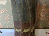 a vase sitting on a table with a floral wallpaper behind it