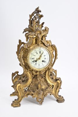 une horloge en or posée sur une surface blanche