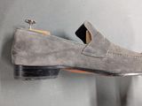 grey sued loafer shoes hanging on a gray wall