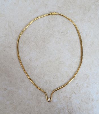 un gros plan d'un collier en or posé sur une surface en marbre