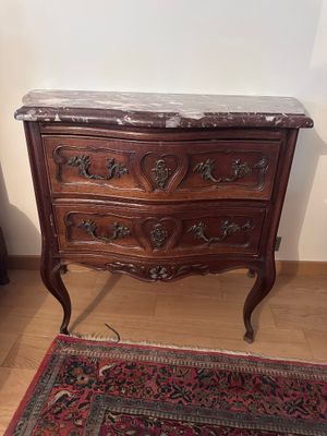 une commode au plateau en marbre posée à côté d'un tapis posé à même le sol