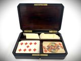 an open wooden box with playing cards inside of it on a white surface