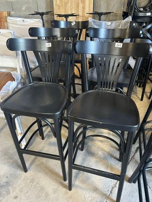 six tabourets de bar en métal noir dans une pièce où il y a beaucoup de chaises