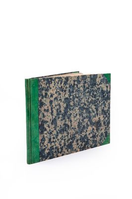 an old book with a green cover sitting on top of a white surface