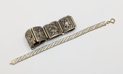 an antique silver bracelet and a silver bracelet on a white surface