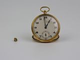 une montre de poche en or posée sur une surface blanche