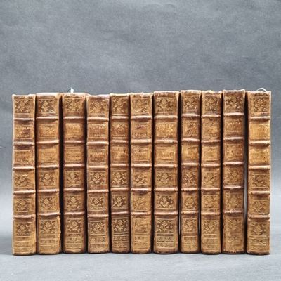 several old books are lined up in a row on a gray surface