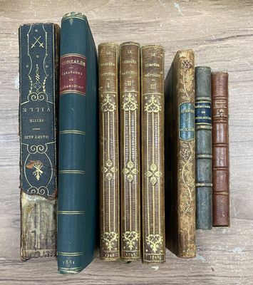 Plusieurs vieux livres sont alignés sur une étagère posée sur une table en bois