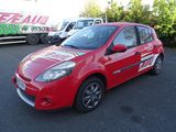 La voiture rouge est garée sur le parking, à côté du camion.