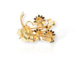 un gros plan d'une broche en or ornée de fleurs
