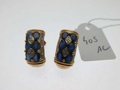 une paire de boucles d'oreilles ornées de pierres bleues et de diamants sur fond blanc