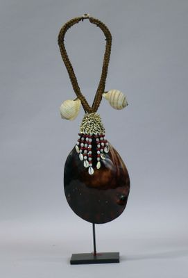 a brown vase with shells on it on a stand
