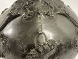 a silver vase that is sitting on a white surface