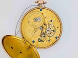 a close up of a pocket watch on a white surface