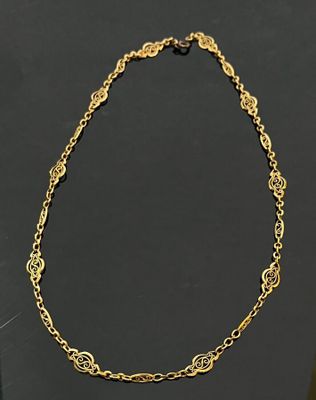 a gold plated necklace with a circular design on a black background
