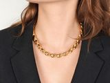 a woman wearing a black blazer and a gold chain necklace