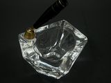 un cendrier en verre muni d'une poignée noire, posé sur une table noire