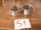 deux ronds de serviette en argent posés sur une table en bois portant le numéro 51