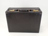 black leather suitcase with gold handles on a white background