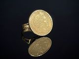 une image représentant une bague avec une pièce d'or posée sur une surface noire