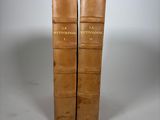 two brown books sitting on top of each other on a white surface