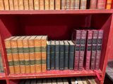de nombreux livres anciens sur une étagère rouge dans une bibliothèque