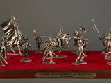 silver figurines of soldiers with flags on display on red carpet