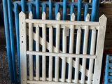 une clôture blanche avec des poteaux bleus devant un mur de briques