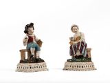deux figurines représentant des personnes assises sur un banc posé sur une surface blanche