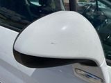 a side view mirror of a white car in a parking lot