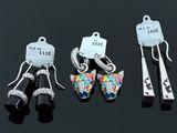 trois paires de boucles d'oreilles et une paire de ciseaux posés sur une surface noire