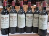 six bottles of red wine are lined up on a table