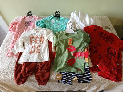 a lot of baby clothes on a bed in a room