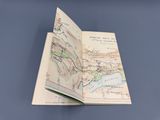 un livre ouvert, sur lequel figure une carte, posé sur une table