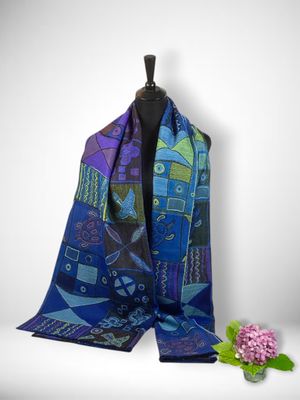 a scarf with a blue and purple design on it next to a flower