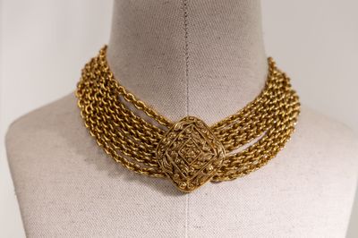 a close up of a gold necklace on a mannequin mannequin