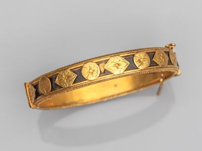 gros plan d'un bracelet en or sur une surface blanche
