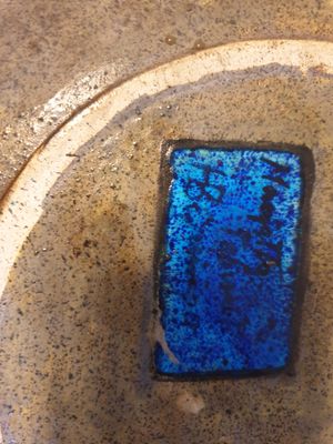 un verre bleu posé sur une assiette, par terre