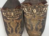 deux paires de chaussures ornées de motifs dorés sur un fond blanc