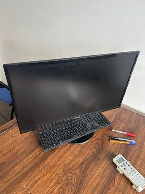 un bureau sur lequel se trouvent un écran, un clavier et une télécommande
